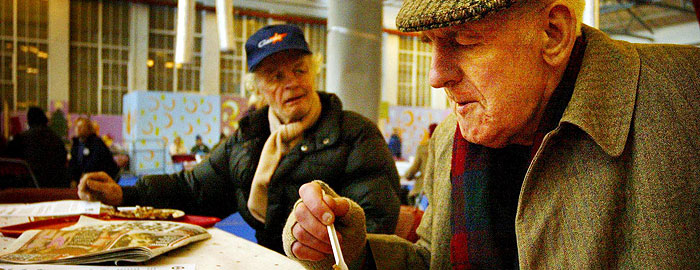 Elderly men eating together at a shelter