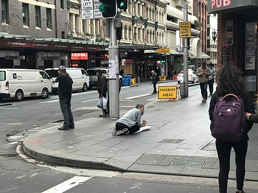 Sydney, Australia, street with beggar and passersby. Credit: Kgbo [CC BY-SA 4.0 (https://creativecommons.org/licenses/by-sa/4.0)]