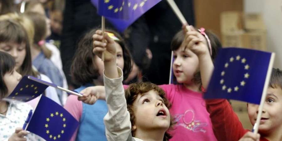 Children waving small EU flags