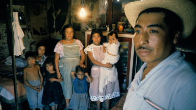 Mexican family: mother, father and 6 children in crowded room.